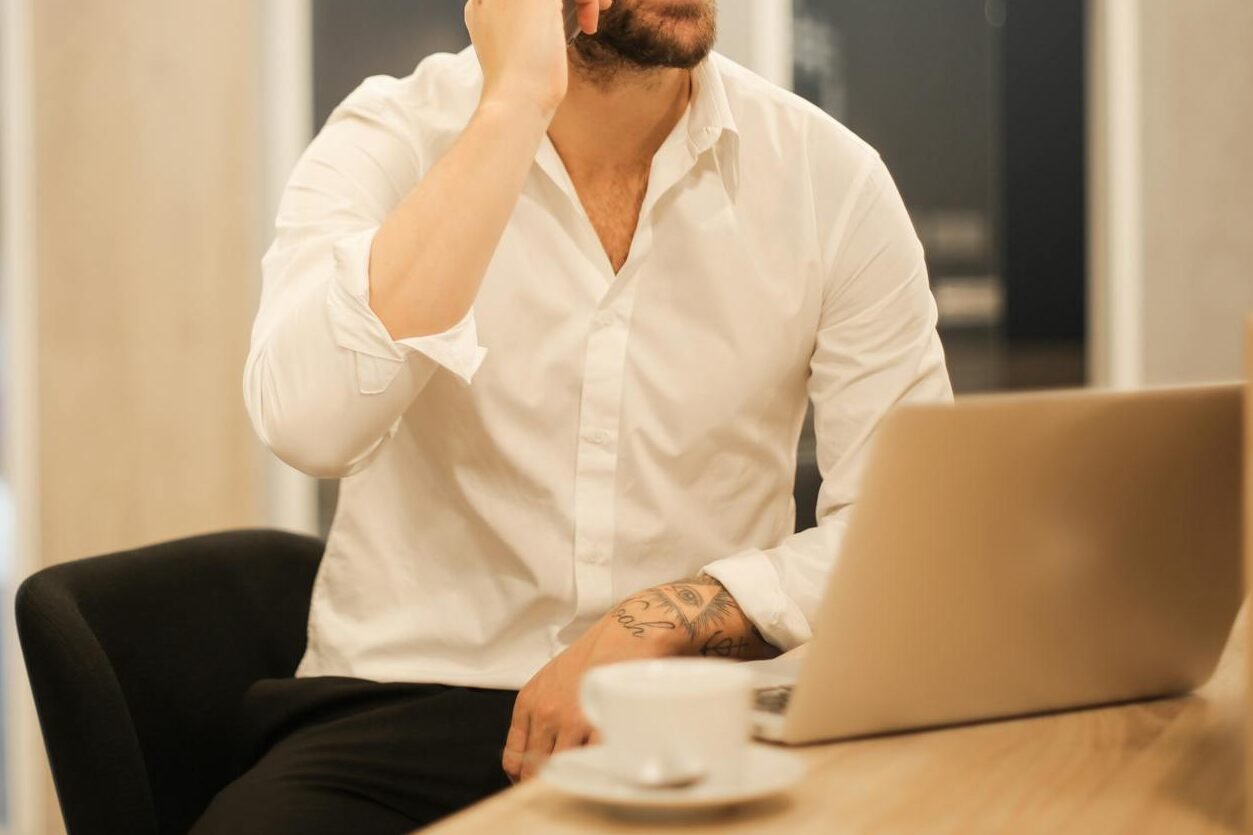 smiling formal male with laptop chatting via phone