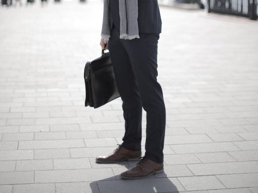 man in black suit holding leather briefcase